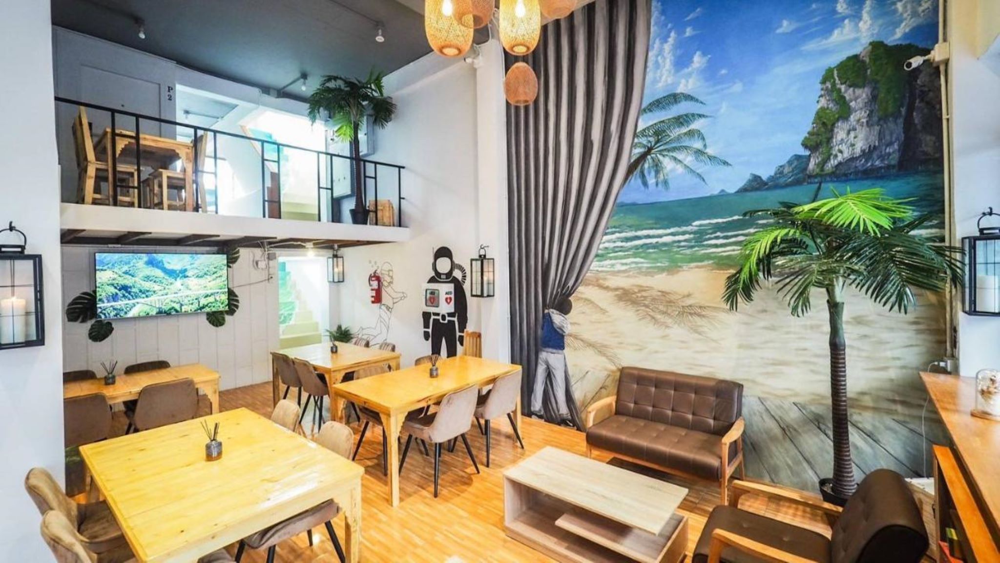 A restaurant with a beach mural, wooden furniture, and a TV screen.