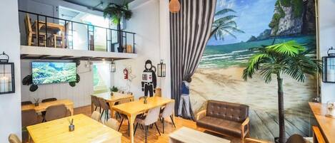 A restaurant with a beach mural, wooden furniture, and a TV screen.