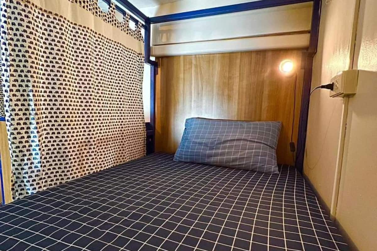 A small, compact room with a bed, a wooden headboard, and a patterned floor.
