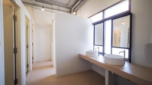 A modern bathroom with two sinks, a large mirror, and a view of the hallway. - Arawana Hoft Hostel (Bangkok)