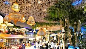 A spacious indoor area with hanging wicker chandeliers, a central seating area, and a ceiling with a net-like structure. - Arawana Hoft Hostel (Bangkok)