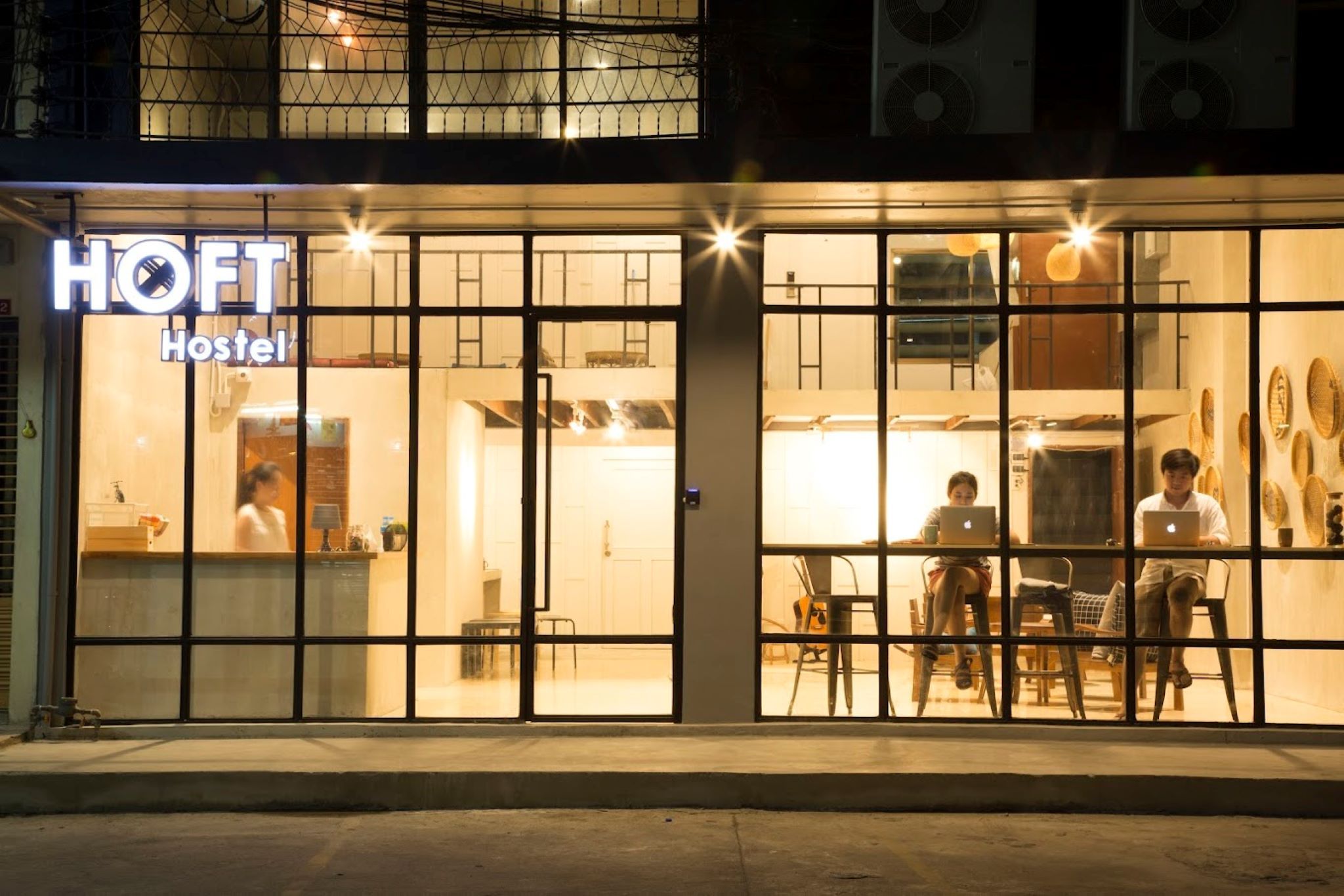 A hostel with a sign reading "HOFT Hostel" and a reception area with a counter and chairs.