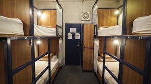A narrow corridor with bunk beds on either side, a door at the end, and a wall-mounted air conditioning unit. - Arawana Hoft Hostel (Bangkok)