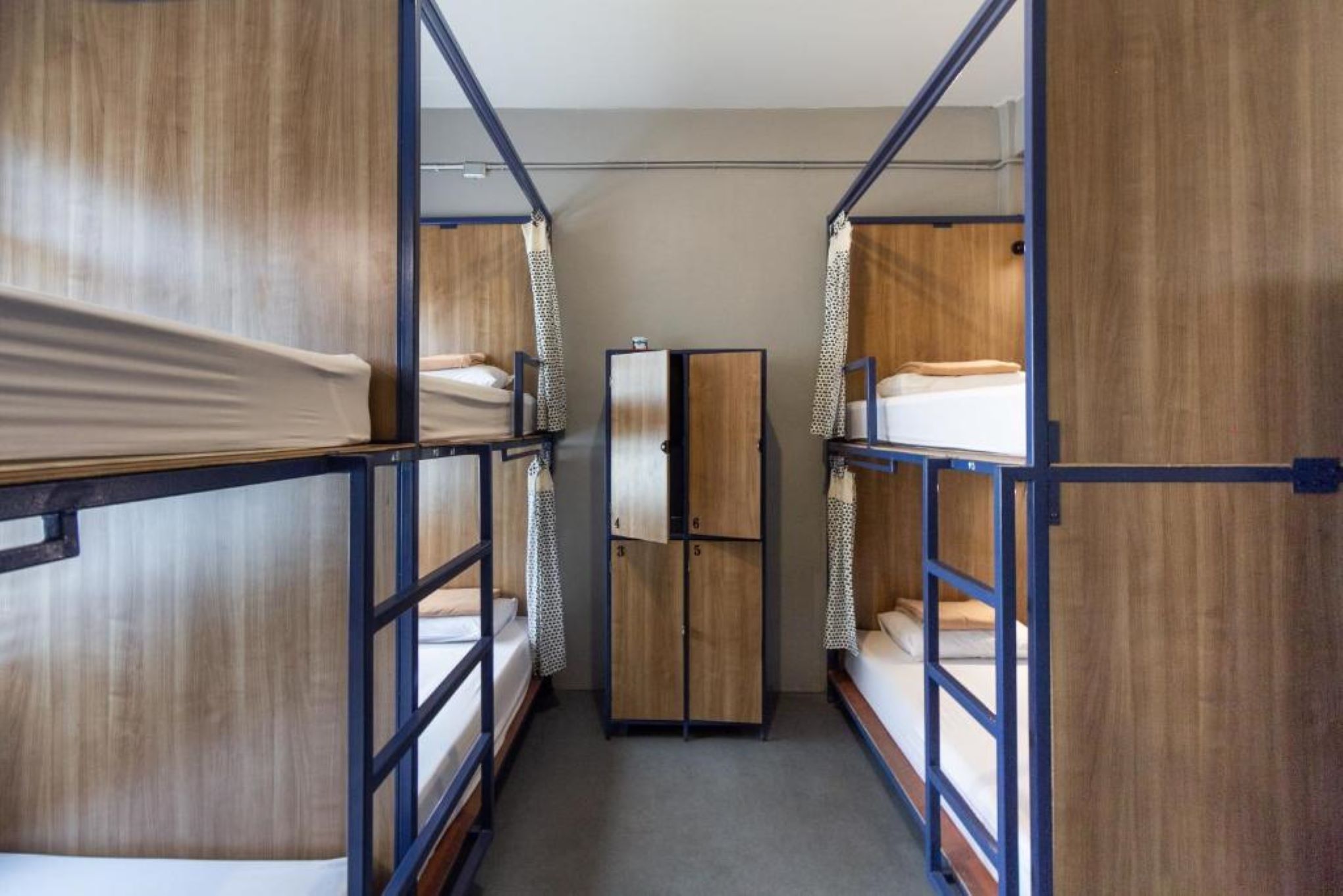 A narrow corridor with bunk beds on either side, a central wardrobe, and a door at the end.