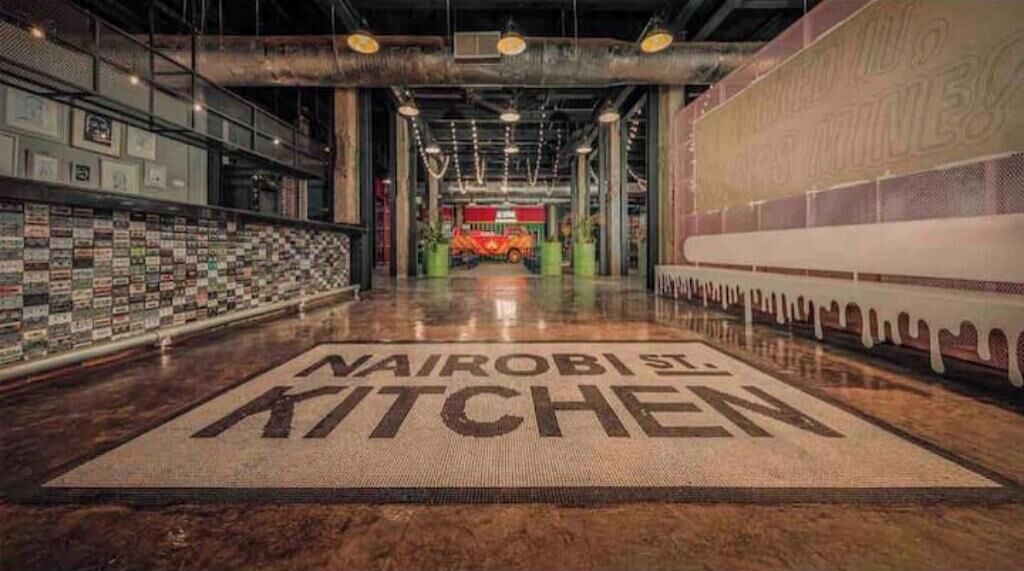 A spacious corridor with a polished floor leading to a restaurant named "Nairobi St Kitchen."