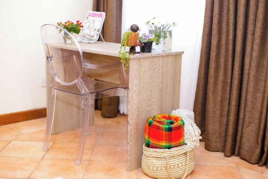 A clear desk with a chair, a small table with decorative items, and a woven basket on the floor.