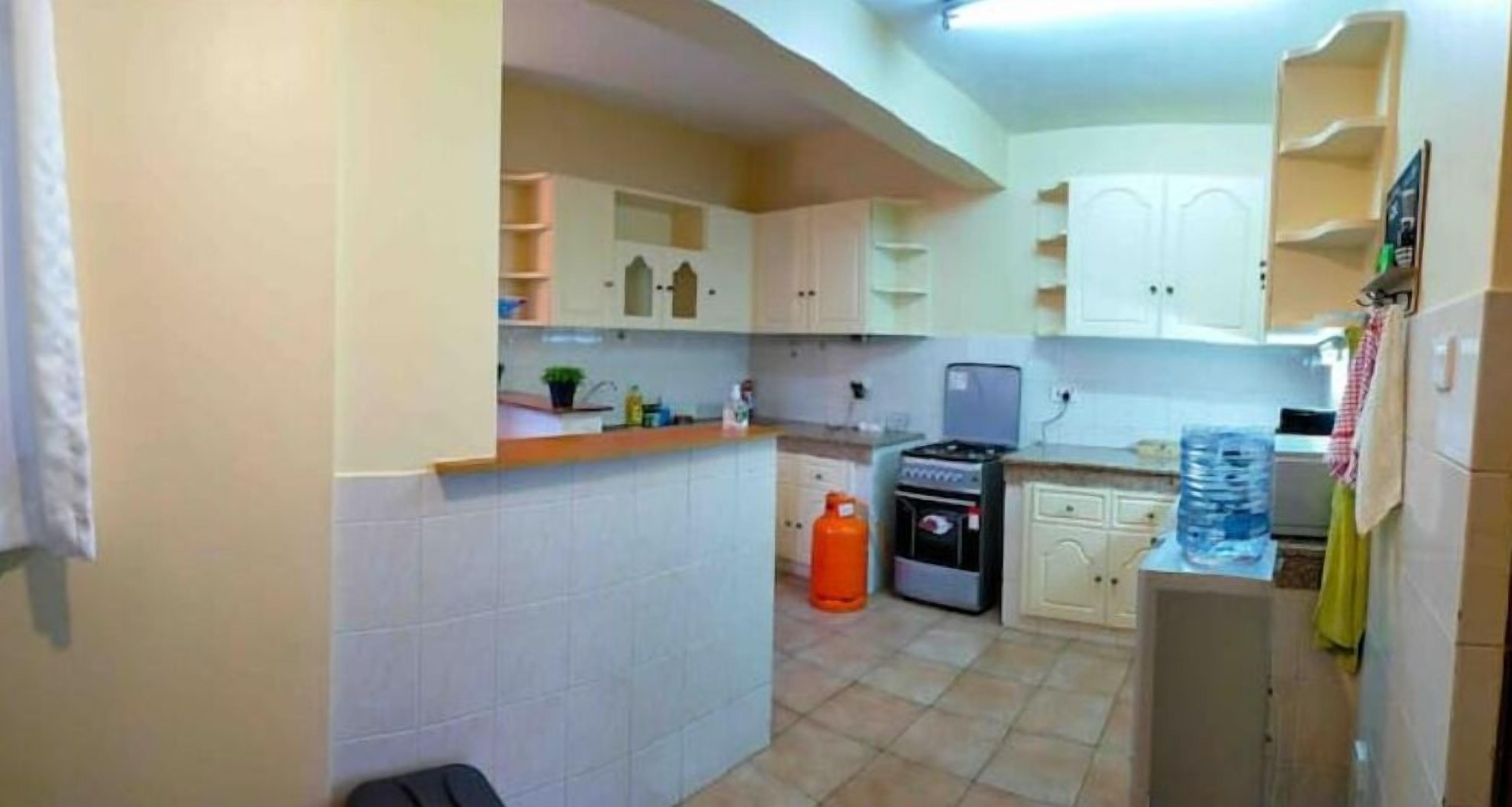 A compact kitchen with white cabinets, a gas stove, and a water dispenser.