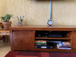 A wooden cabinet with a clock, books, and two potted plants. - Great Value 1BR, Walk to Sarit and Westgate  (Nairobi)
