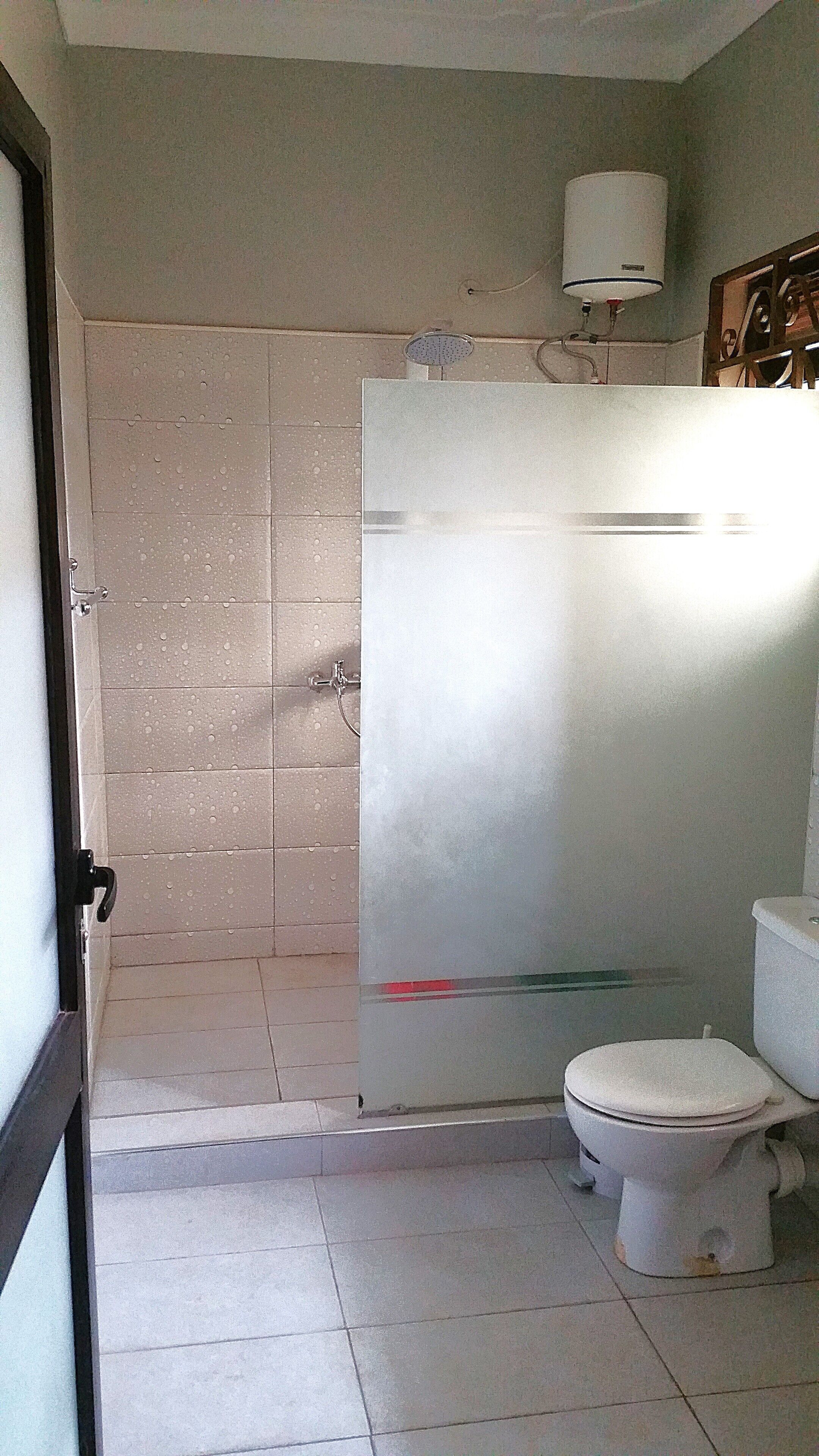 A bathroom with a shower, toilet, and a glass partition.