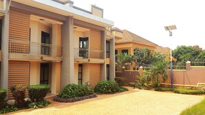 A multi-story building with balconies, a paved driveway, and surrounding greenery. - Serene Retreat with Golf Course, Beach & Wellness Centre Nearby (Akright City)