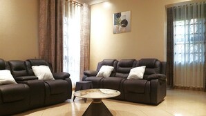 A living room with two dark leather sofas, a small round coffee table, and a painting on the wall. - Serene Retreat with Golf Course, Beach & Wellness Centre Nearby (Akright City)