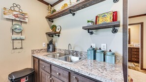A kitchen with granite countertops, stainless steel sinks, wooden cabinets, and decorative items on shelves. - 6 Mi to Topsey Exotic Ranch: Retreat on 12 Acres! (Kempner)