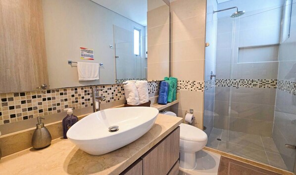 A bathroom with a large white sink, a toilet, and a glass-enclosed shower. - Oceanview Suite Pools Gym Guest Access (Cartagena)