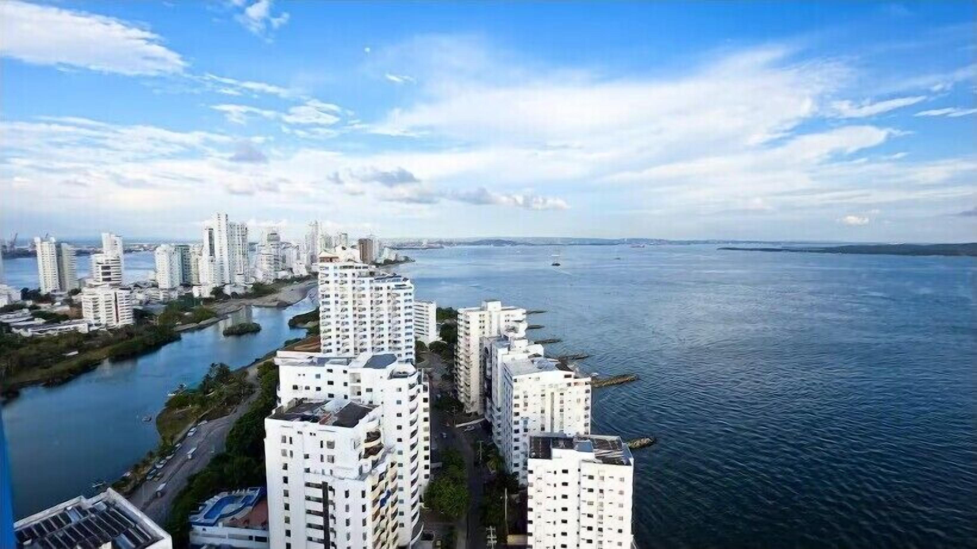 Un paisaje urbano costero con edificios altos, un puerto deportivo y cielo despejado.