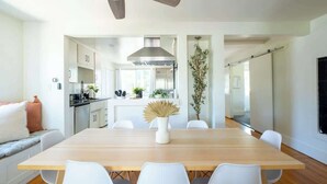 A modern kitchen with white cabinets, a wooden dining table, and a ceiling fan. - Spacious Central & Chic 5BR w/ Luxe Outdoor Living (San Diego)