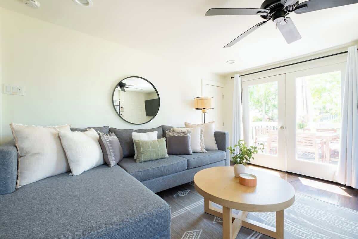A living room with a grey sofa, a round mirror, a lamp, and a coffee table.