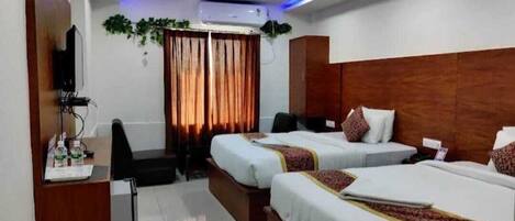 A hotel room with two beds, a desk with a chair, a television, and a window with curtains.