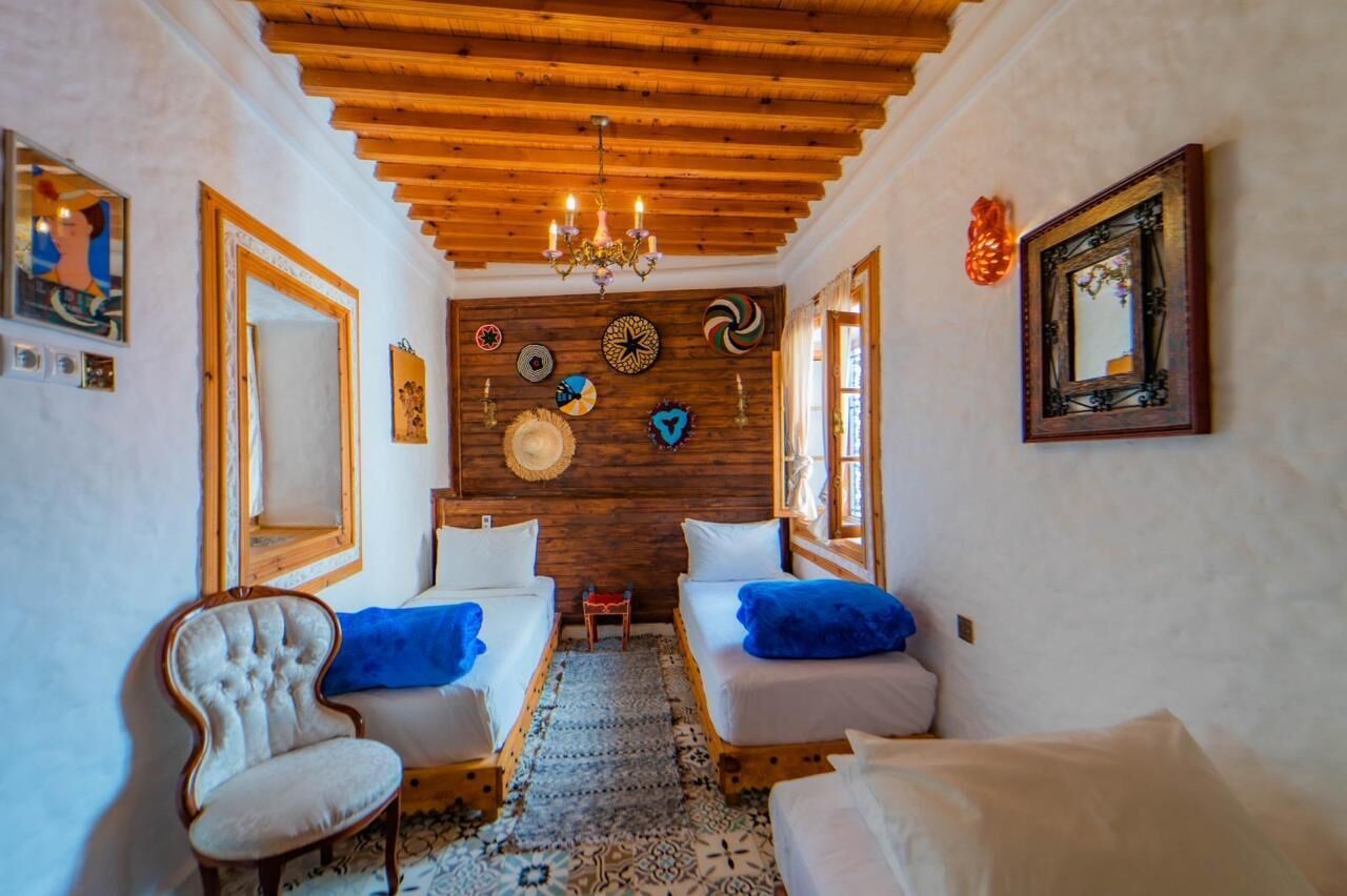 A cozy room with two beds, a chandelier, and a wooden ceiling.