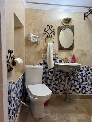 A bathroom with a toilet, sink, and mirror.