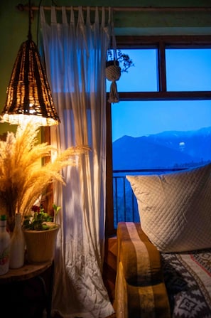 Relax in a serene mountain view room with a large window, a cozy couch, and a hanging lamp.