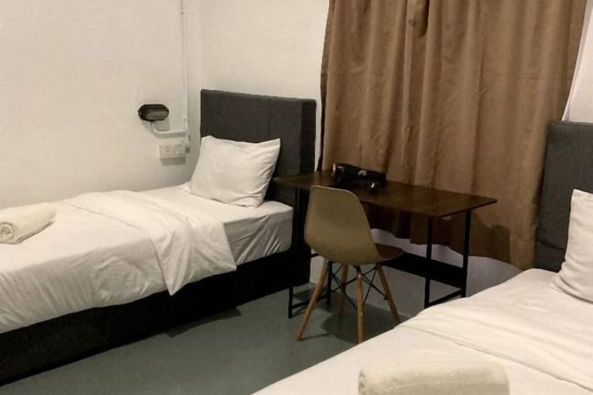 A single bed with a headboard, a desk with a chair, and a curtain.