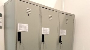 A row of grey metal lockers with numbered compartments, each with a keyhole and a small label. - 39 Love Lane - Smart Intelligent Inn (George Town)