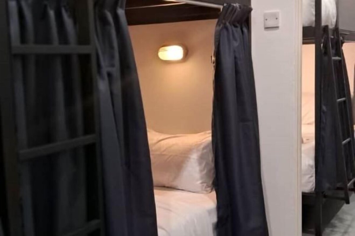 A bunk bed room with a single bed, a light fixture, and a power outlet on the wall.