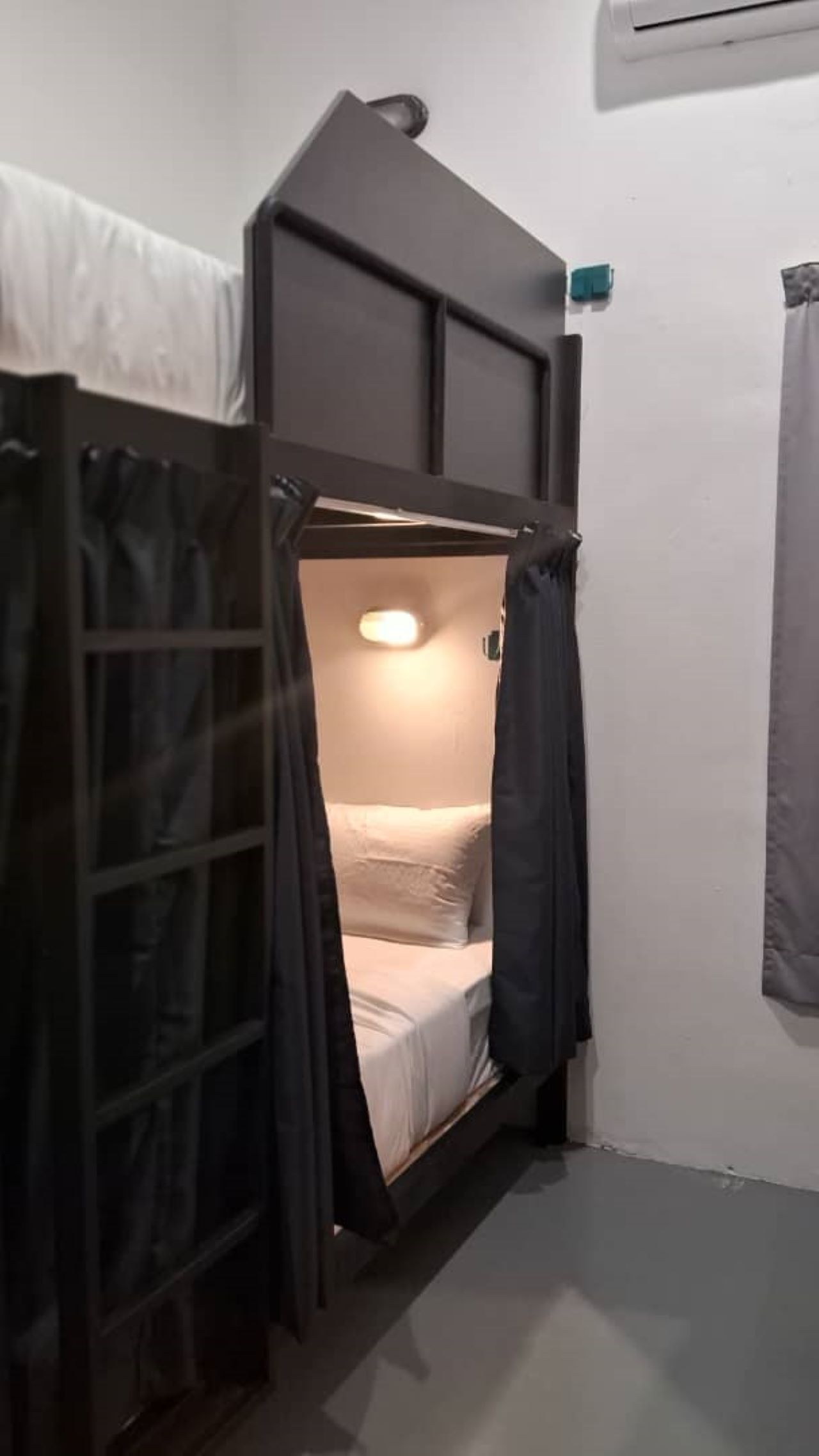 A small, enclosed bunk bed room with a slanted ceiling and a single light fixture.