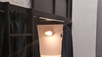 A small, enclosed bunk bed room with a slanted ceiling and a single light fixture.