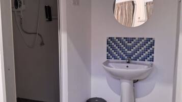 A bathroom with a white pedestal sink, a mirror, and a tiled backsplash.