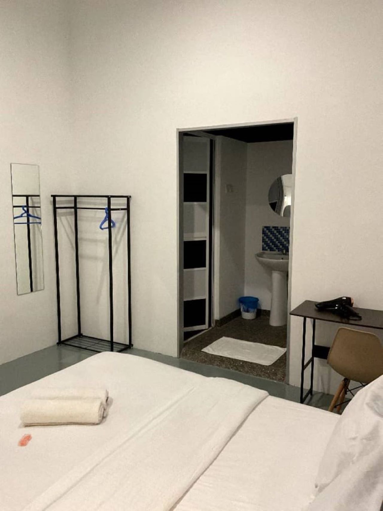 A hotel room with a bed, a desk, a chair, a wardrobe, and a bathroom visible through an open door.