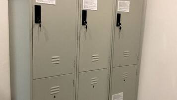 A row of grey metal lockers with numbered compartments, each with a keyhole and a small label.