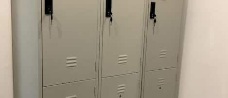 A row of grey metal lockers with numbered compartments, each with a keyhole and a small label.