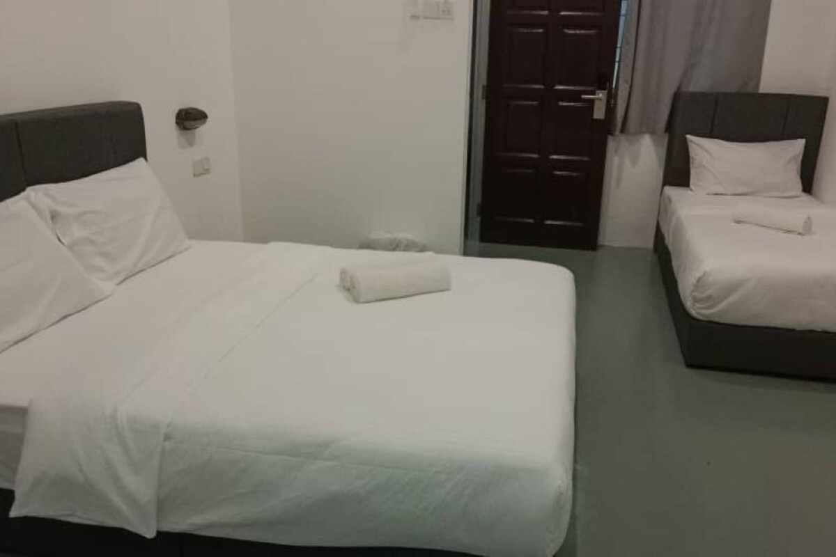A hotel room with two beds, each with white bedding and a dark headboard.