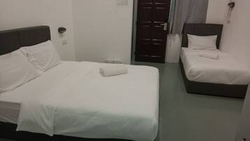 A hotel room with two beds, each with white bedding and a dark headboard.