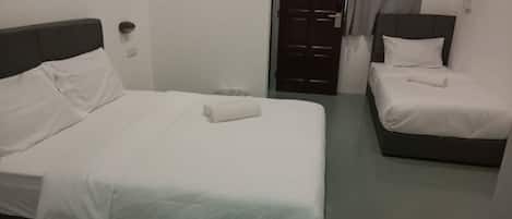 Habitación de hotel con dos camas, cada una con ropa de cama blanca y cabeceros oscuros.