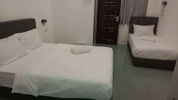 Ein Hotelzimmer mit zwei Betten, jeweils mit weißer Bettwäsche und einem dunklen Kopfteil.