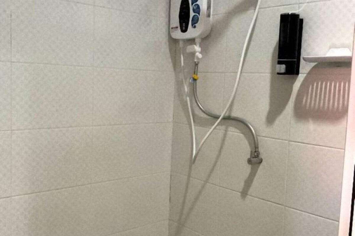 Ein gefliester Duschbereich mit Duschbrause, Seifenspender an der Wand und Handtuchhalter.