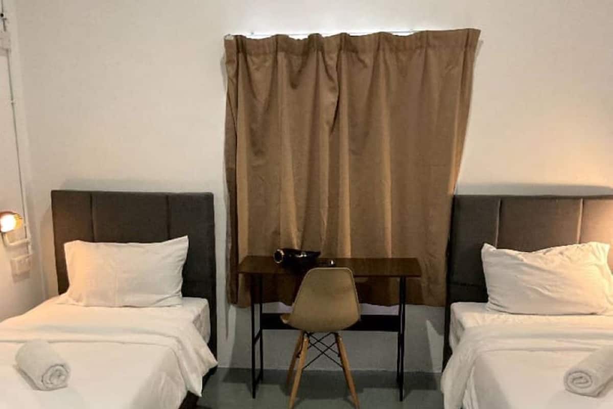 Hotellihuone, jossa on kaksi sänkyä, työpöytä ja tuoli.