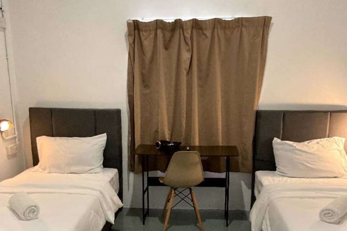 A hotel room with two beds, a desk, and a chair.