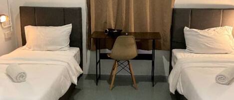 A hotel room with two beds, a desk, and a chair.