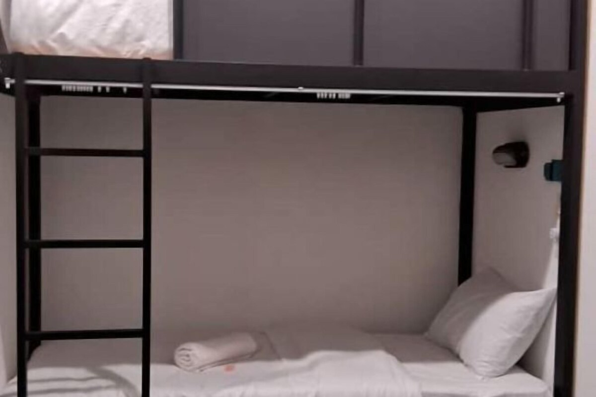 Ein Stockbett mit einer Leiter, einem Kopfkissen und einem zusammengerollten Handtuch.