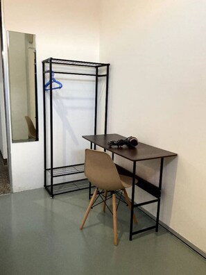 Une pièce de taille modeste, équipée d’une armoire pliante, d’une petite table et d’une chaise.