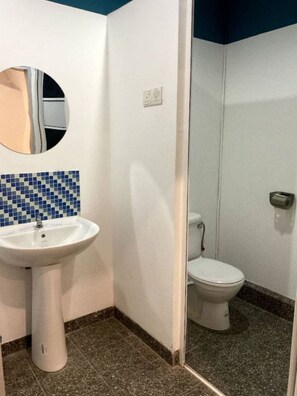A bathroom with a white sink, a toilet, and a mirror. - 39 Love Lane - Smart Intelligent Inn (George Town)
