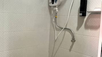 A shower area with a handheld showerhead, a wall-mounted control panel, and a handheld soap dispenser.