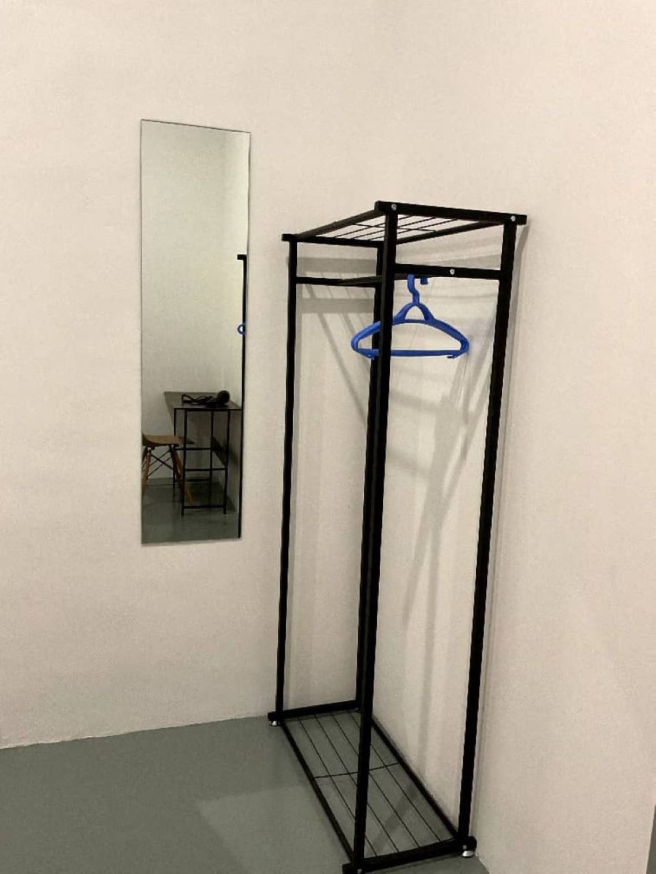 Ein Eckzimmer mit einem Metallschrank, einem Spiegel und einem kleinen Tisch.