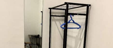 Habitación de esquina con armario metálico, espejo y una mesita.