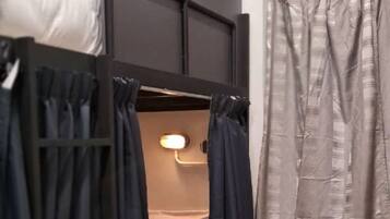 A bunk bed with curtains, a bedside lamp, and an air conditioning unit.