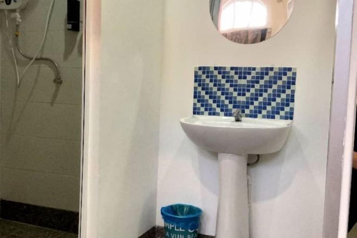 A bathroom with a white sink, blue checkered tiles, and a blue trash bin.