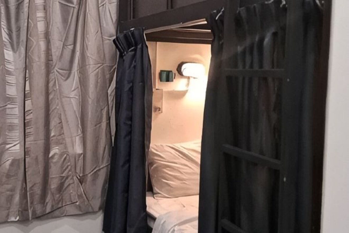 Ein Zimmer mit einem Bett, Vorhängen und einer Wandlampe.